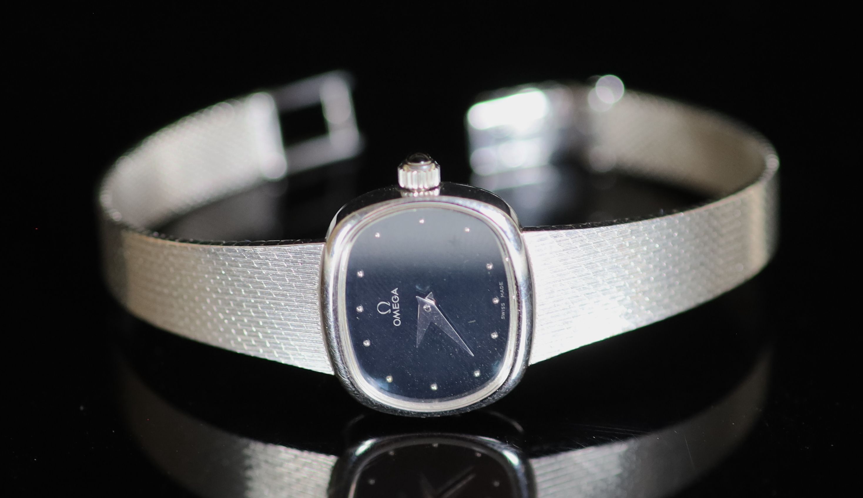 A lady's modern 9ct white gold Omega manual wind wrist watch, on an integral Omega 9ct white gold bracelet